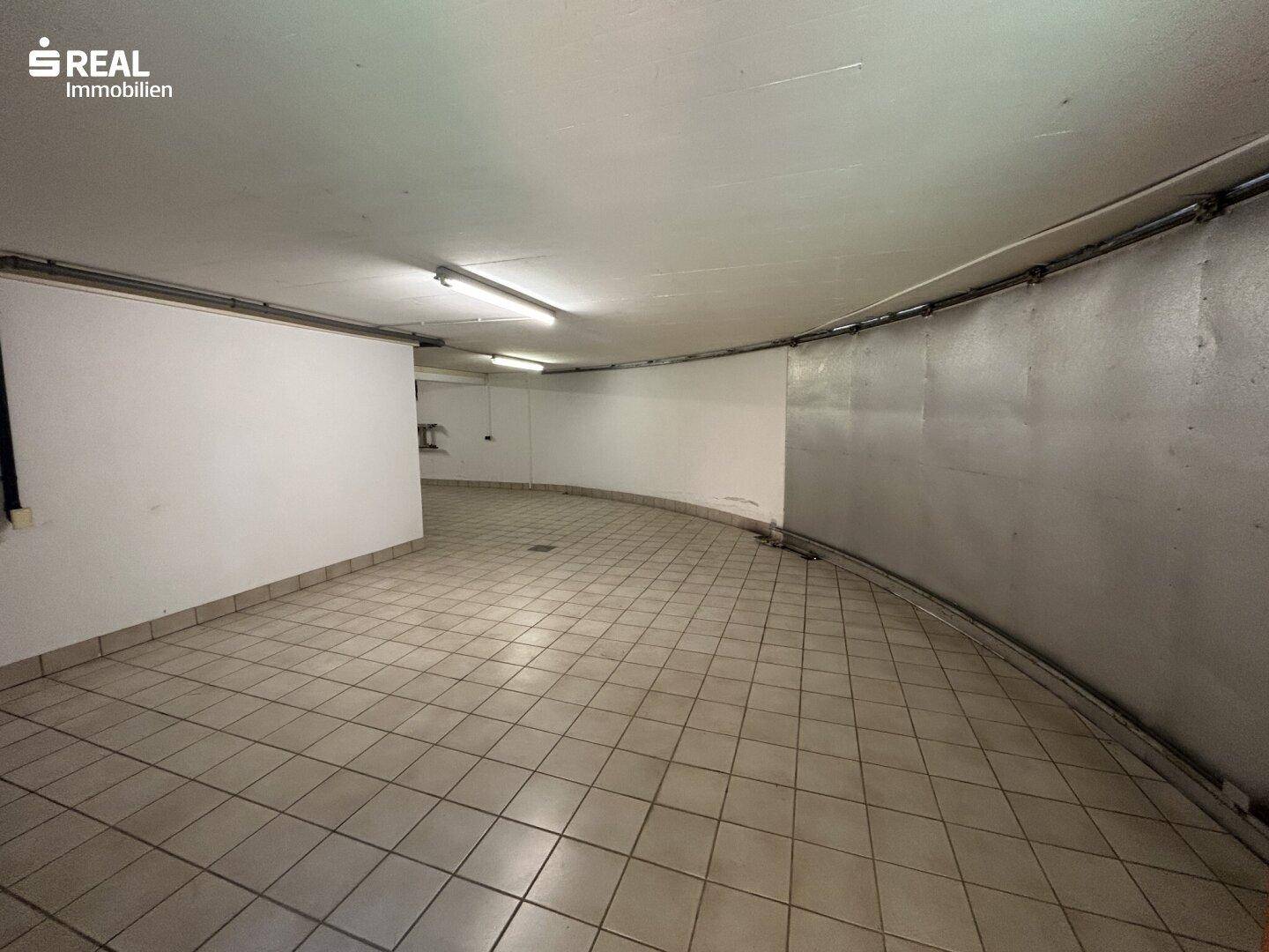 Geräumige Garage mit Fliesenboden und ausreichend Platz für Fahrzeuge.