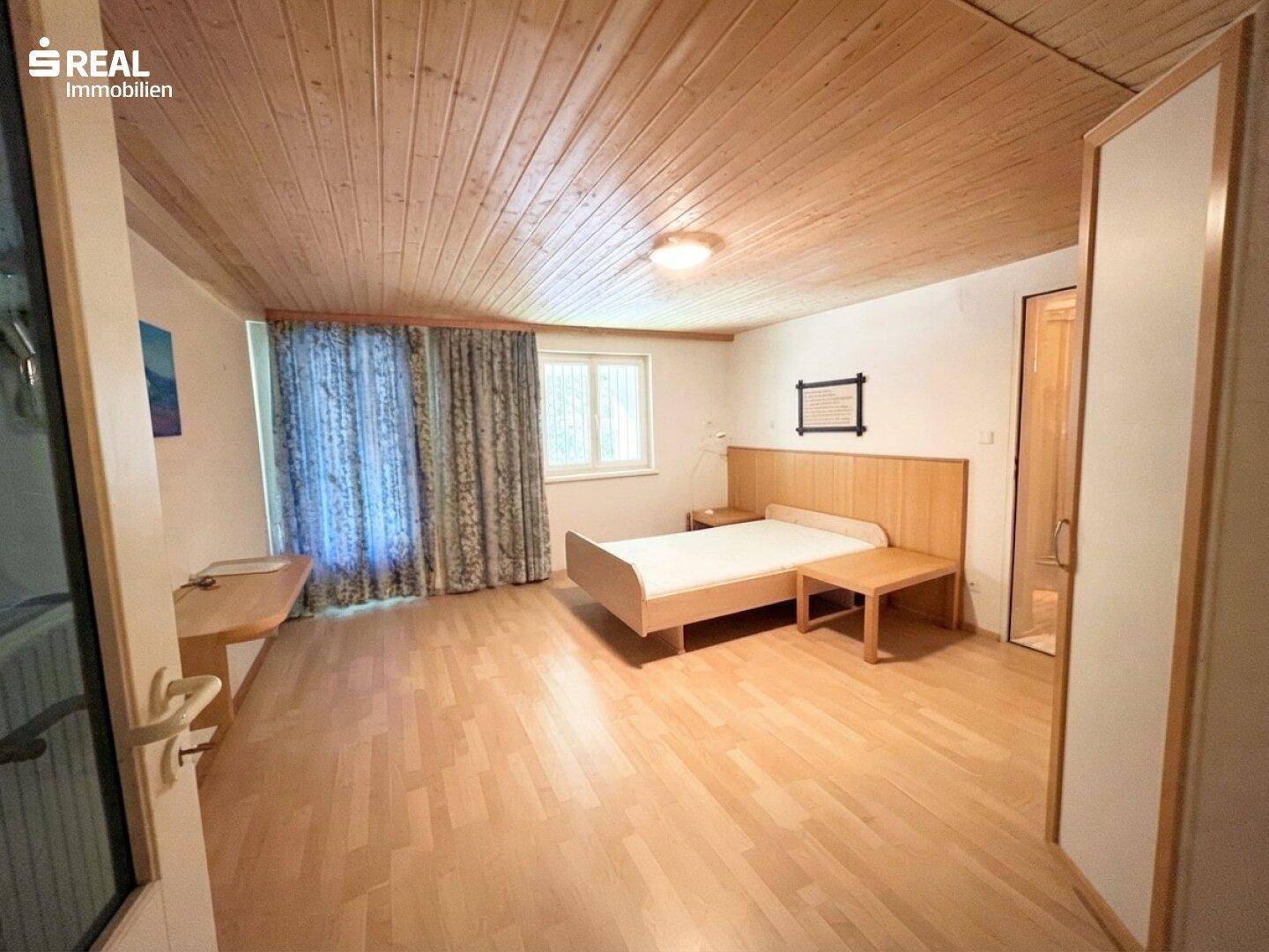 Schlafzimmer mit Holzboden, Holzdecke und Bettgestell.