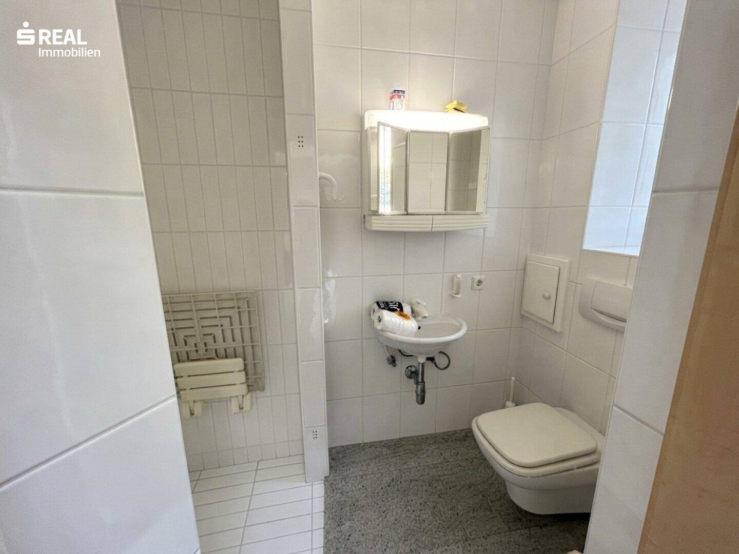 Gäste-WC mit Waschbecken, Toilette und gefliesten Wänden.