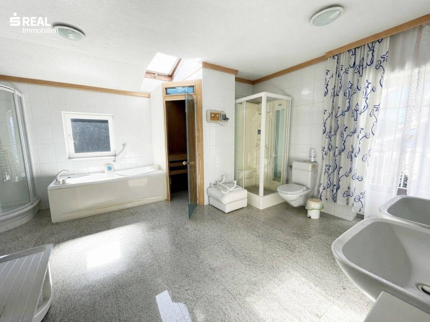 Großes Badezimmer mit Badewanne, Dusche, Doppelwaschbecken und integrierter Sauna.