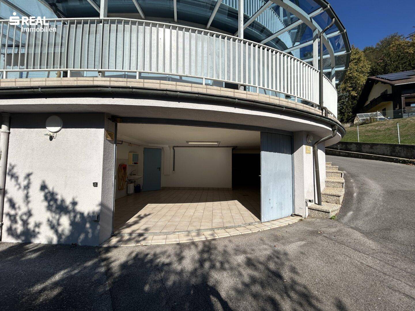Offene Garage mit Fliesenboden und direktem Zugang zum Haus.