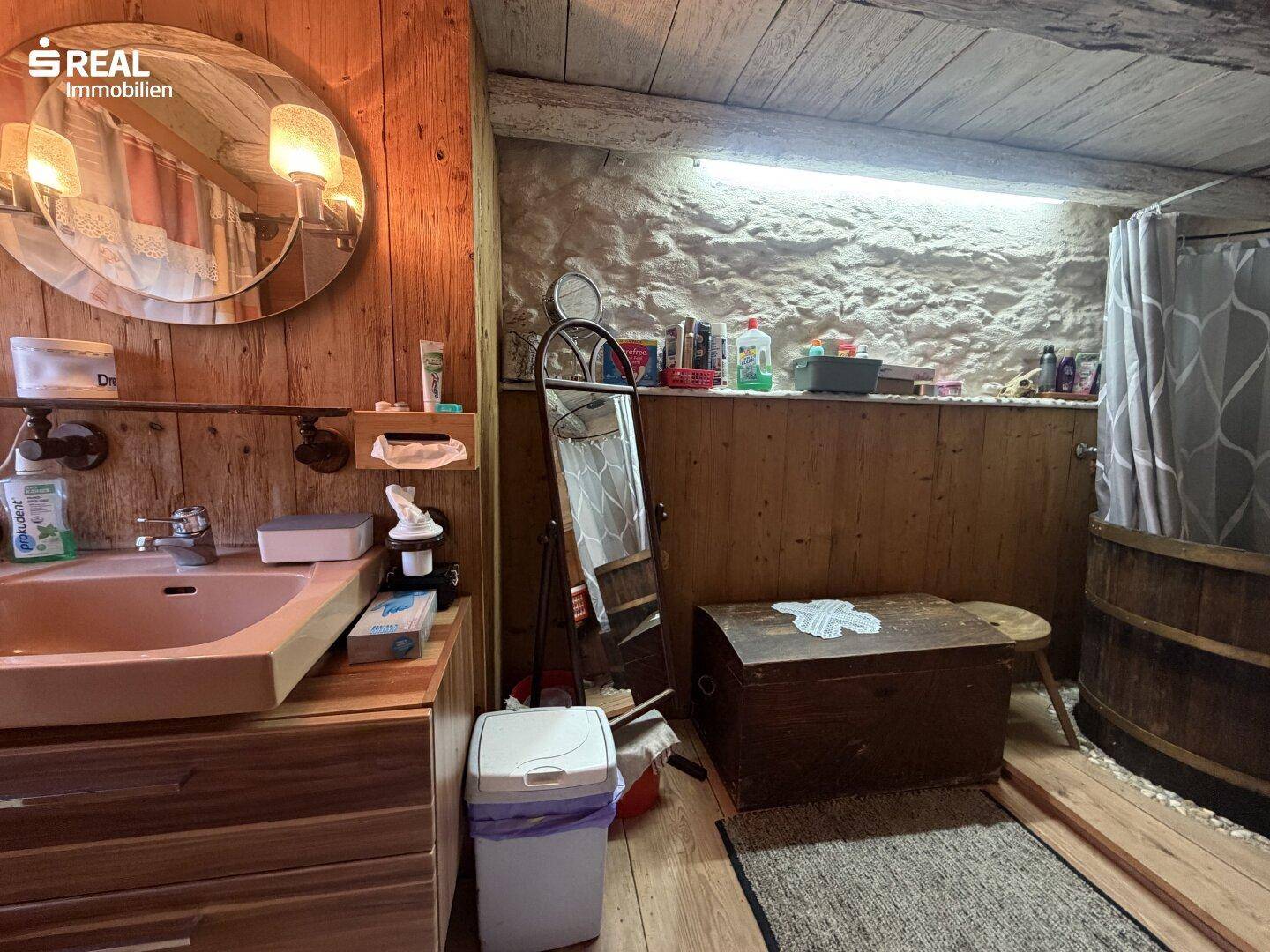 Rustikales Badezimmer mit Holzverkleidung, Einzelwaschbecken und Duschbereich, einfach gehalten.