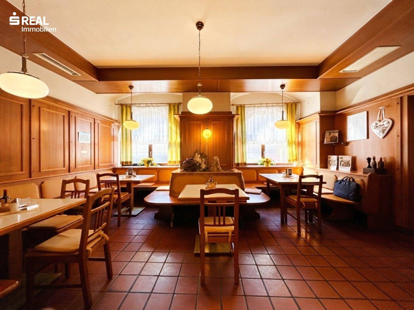 Gemütlicher Gastraum im traditionellen Stil mit Holztäfelung, rustikalen Möbeln und Terrakotta-Fliesenboden.