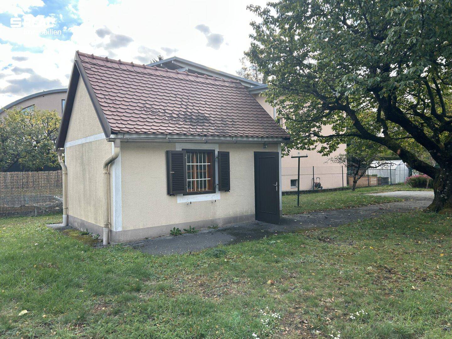 Kleines Nebengebäude im Garten mit Fensterläden und separatem Eingang.