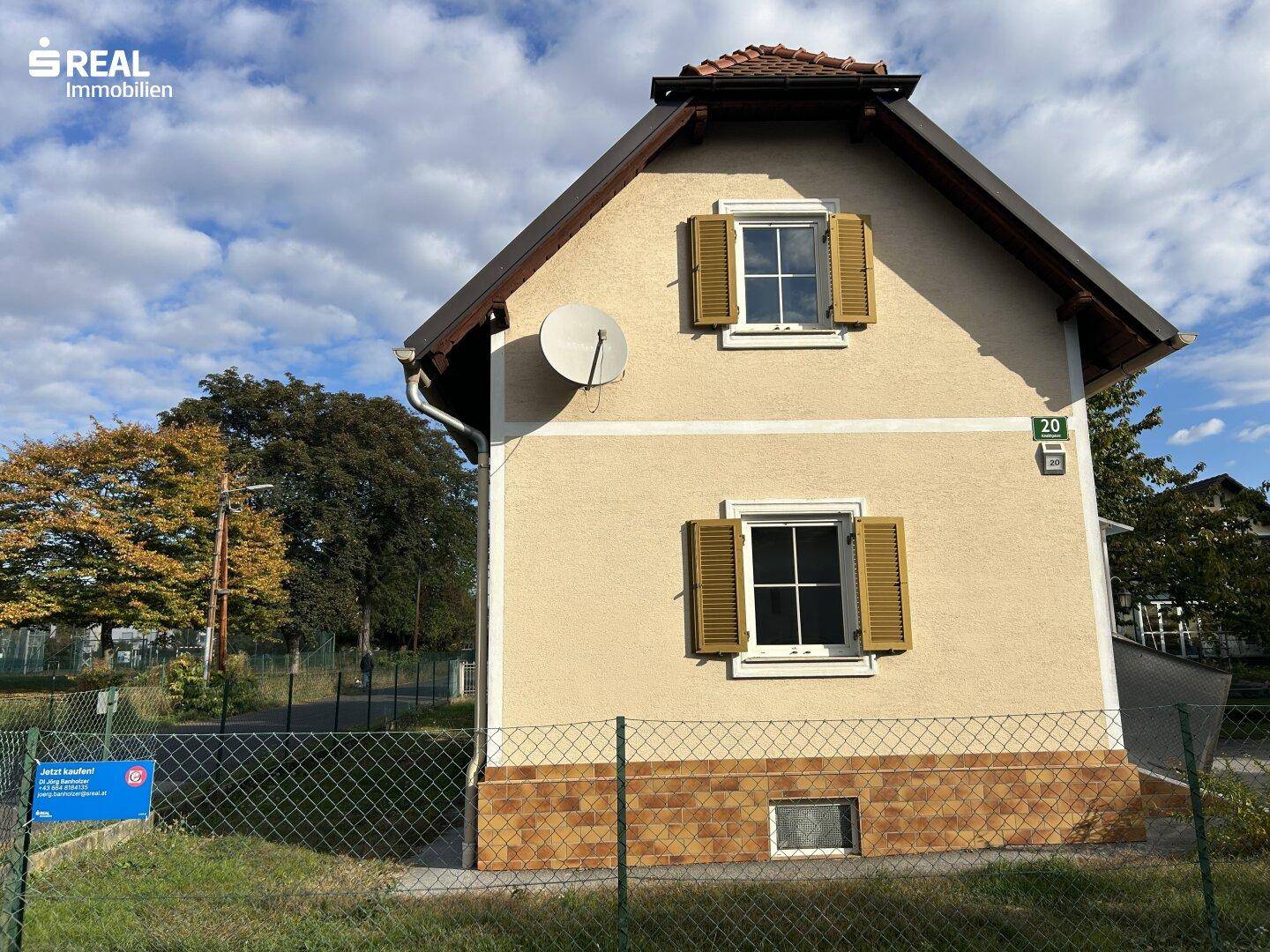 Giebelseite des Hauses mit Fensterläden, Satteldach und Blick auf die grüne Umgebung.