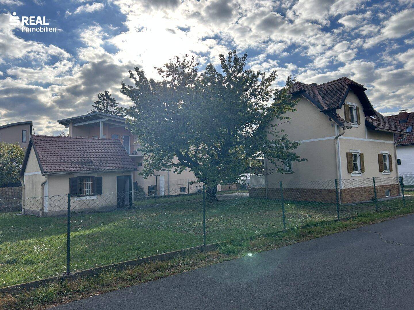 Gesamtansicht des Hauses und Nebengebäudes mit großem Garten und altem Baum.