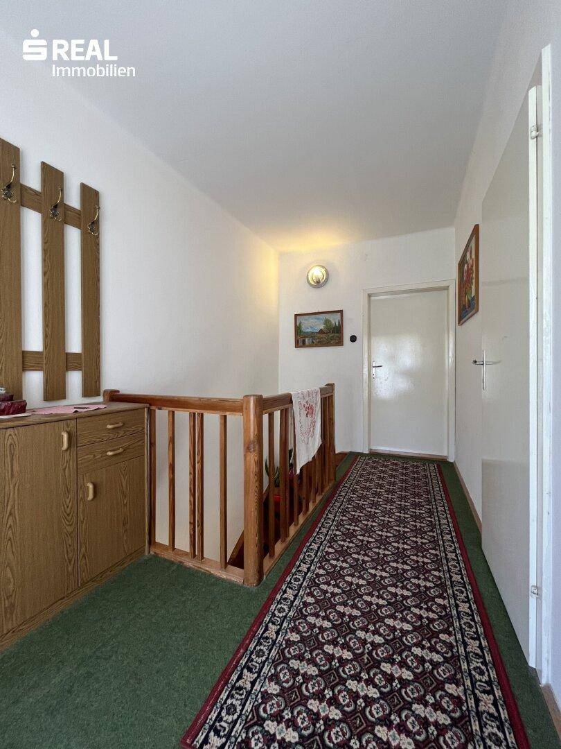 Geräumiger Flur im Obergeschoss mit Garderobe und Teppichboden, hell und funktional eingerichtet.