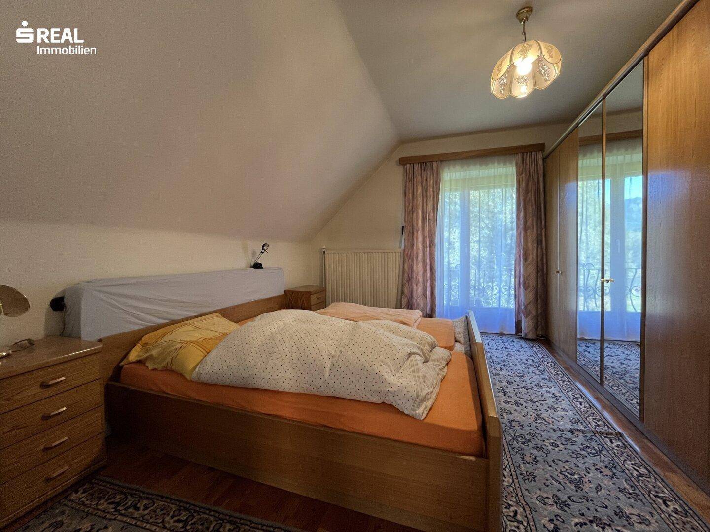 Gemütliches Schlafzimmer im Dachgeschoss mit Doppelbett, Kleiderschrank und Holzboden, einladend.