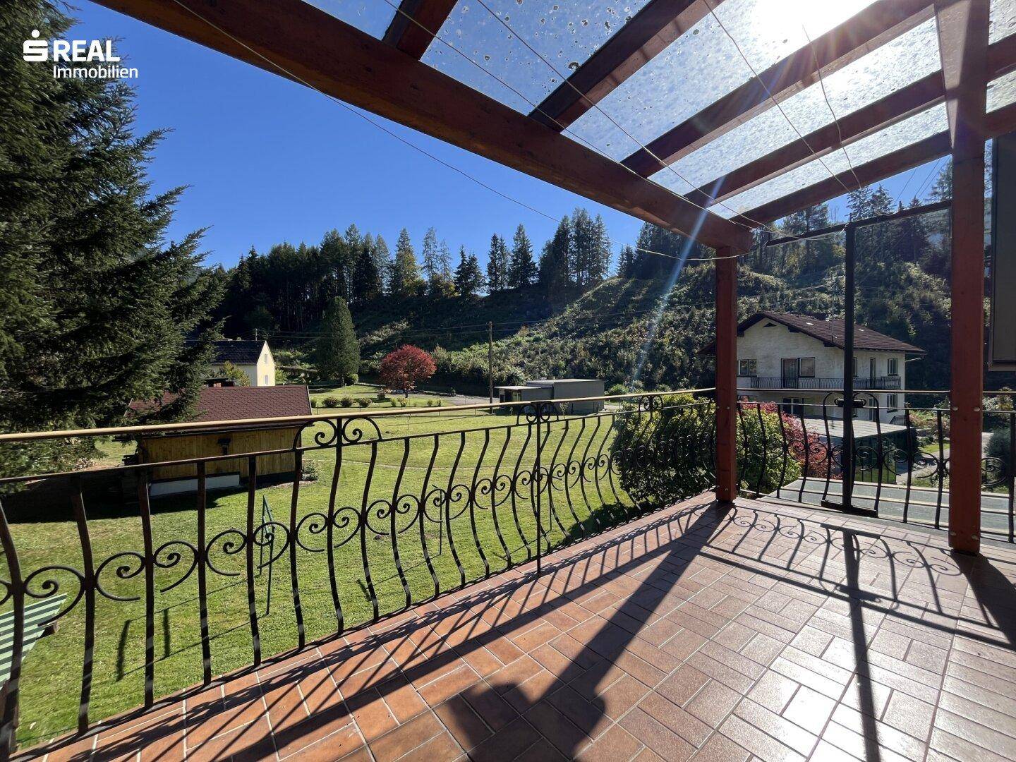 Sonniger Balkon mit Ziegelboden und weitem Ausblick auf die ländliche Umgebung.
