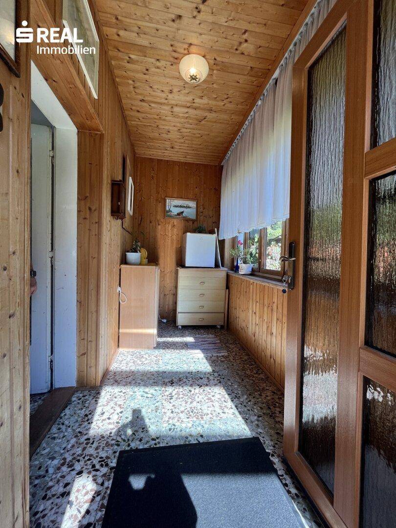 Eingangsbereich des Wintergartens mit Holzvertäfelung und Fliesenboden, hell und einladend gestaltet.