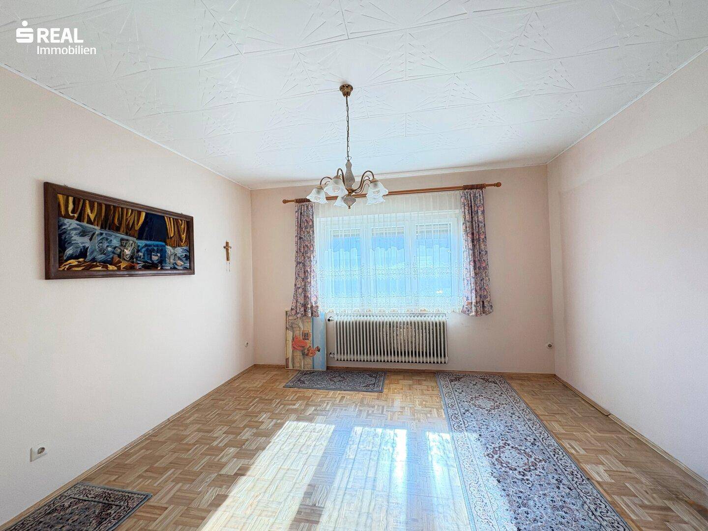 Geräumiges Schlafzimmer mit Parkettboden, großem Fenster und traditioneller Deckenleuchte.