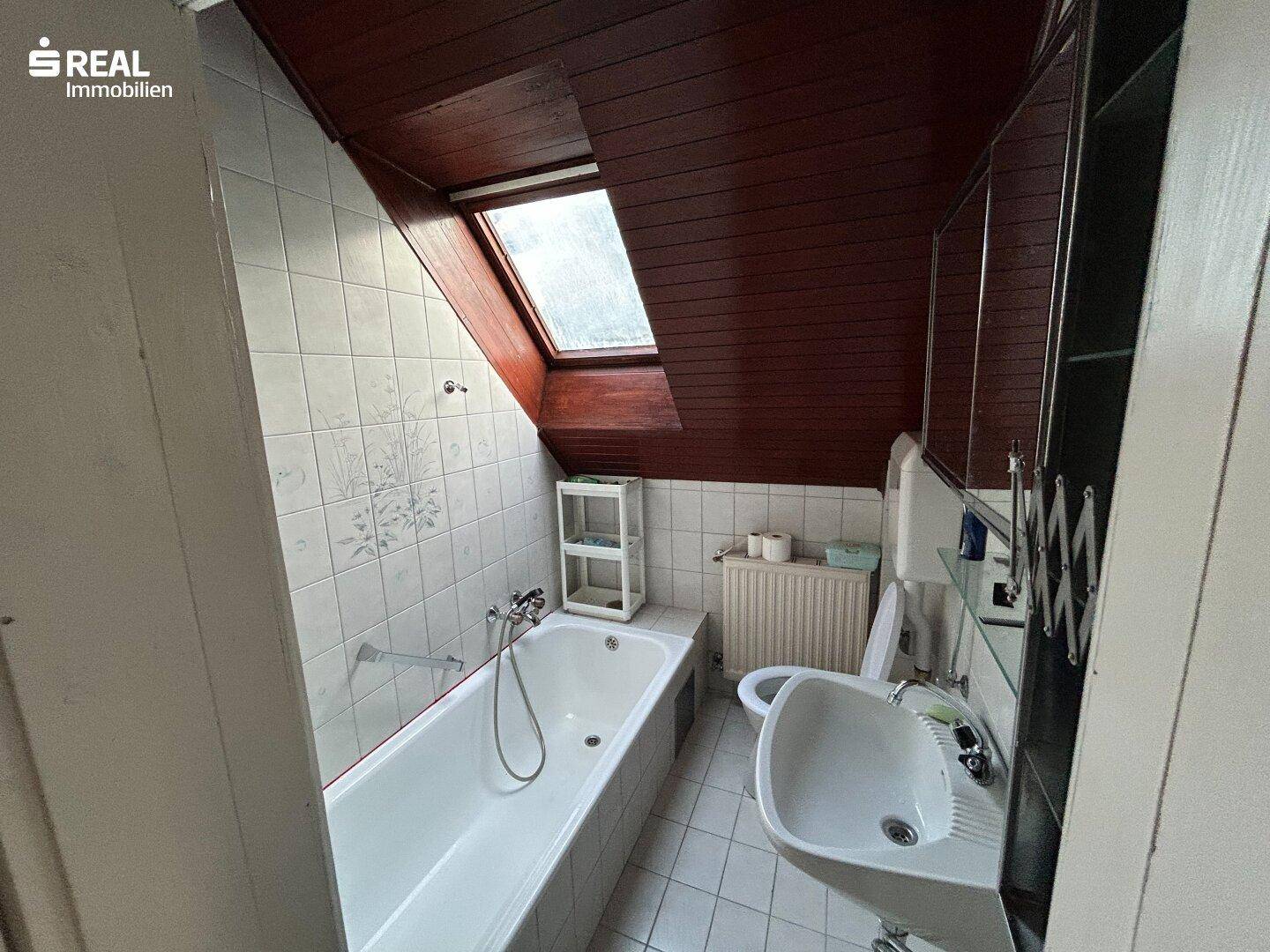Badezimmer im Dachgeschoss mit Badewanne, Waschbecken, WC und Dachfenster.