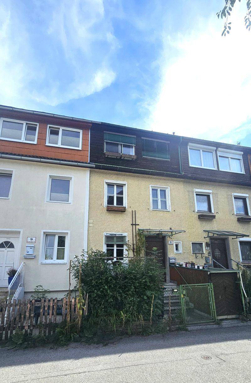 Fassade einer Reihe von Wohnhäusern mit Fenstern und Eingangsbereichen an einem sonnigen Tag.