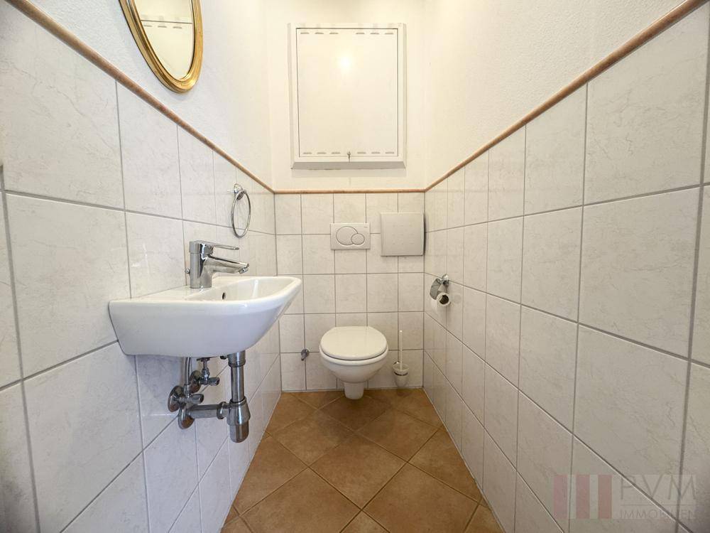 Kleines Gäste-WC mit Fliesenboden, Wandfliesen und einem kompakten Waschbecken.