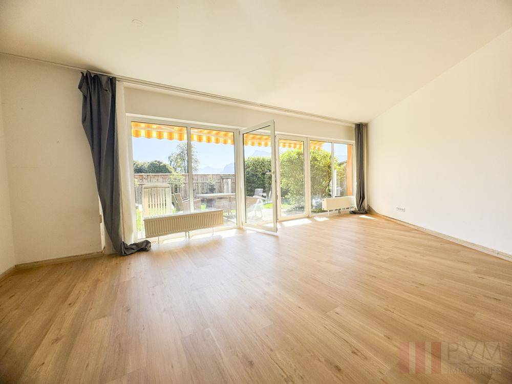 Lichtdurchflutetes Wohnzimmer mit Laminatboden und direktem Zugang zur sonnigen Terrasse.