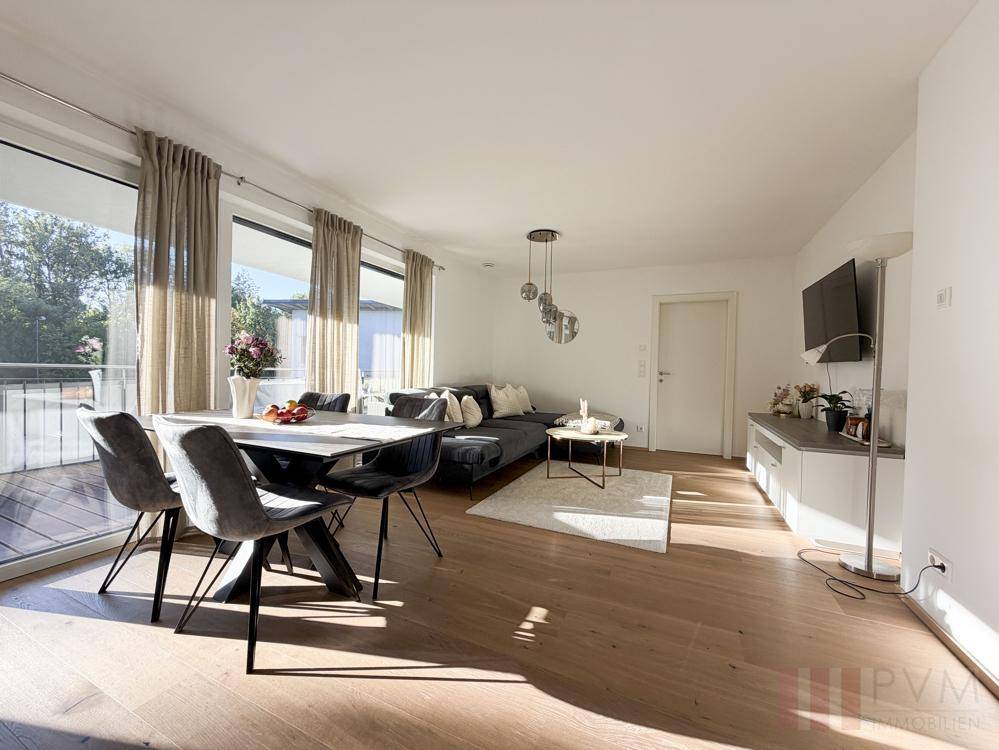Lichtdurchfluteter Wohn- und Essbereich mit großen Fenstern und Zugang zum Balkon.