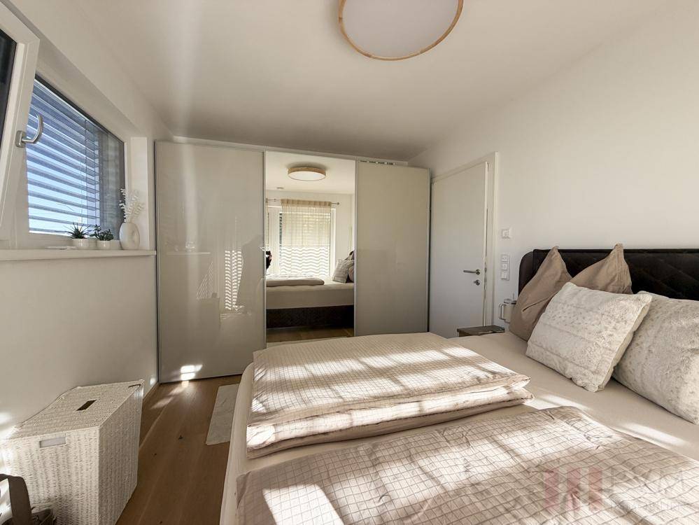Helles Schlafzimmer mit großem Bett, modernen Spiegelschränken und viel Tageslicht.