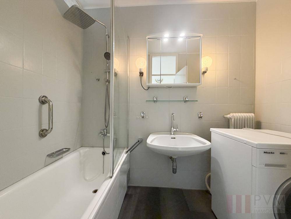 Badezimmer mit Badewanne, Duschfunktion, Waschbecken und Waschmaschine.