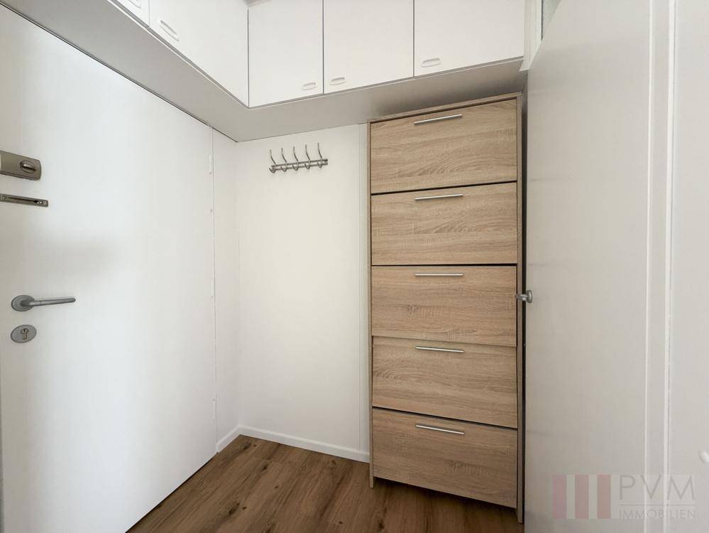 Eingangsbereich mit Laminatboden, Schuhschrank und Garderobenhaken an der Wand.