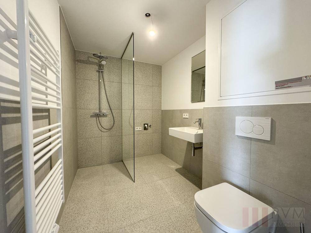 Modernes Badezimmer mit begehbarer Dusche, Wand-WC und beheiztem Handtuchhalter.