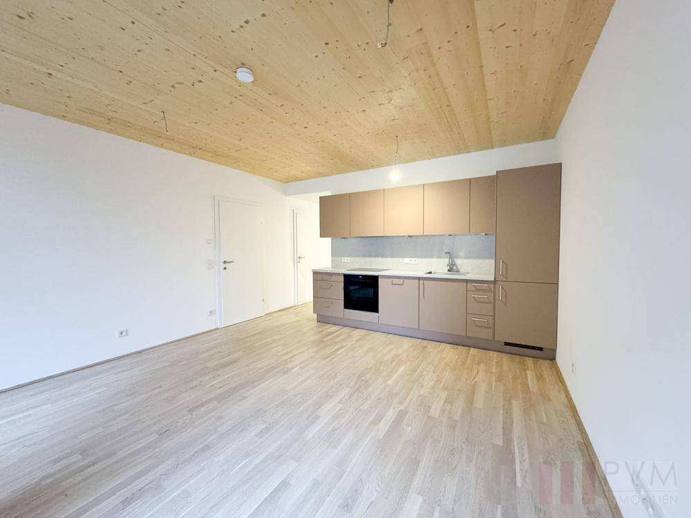 Moderne Einbauküche in hellem Beige mit integrierten Geräten und Holzboden.