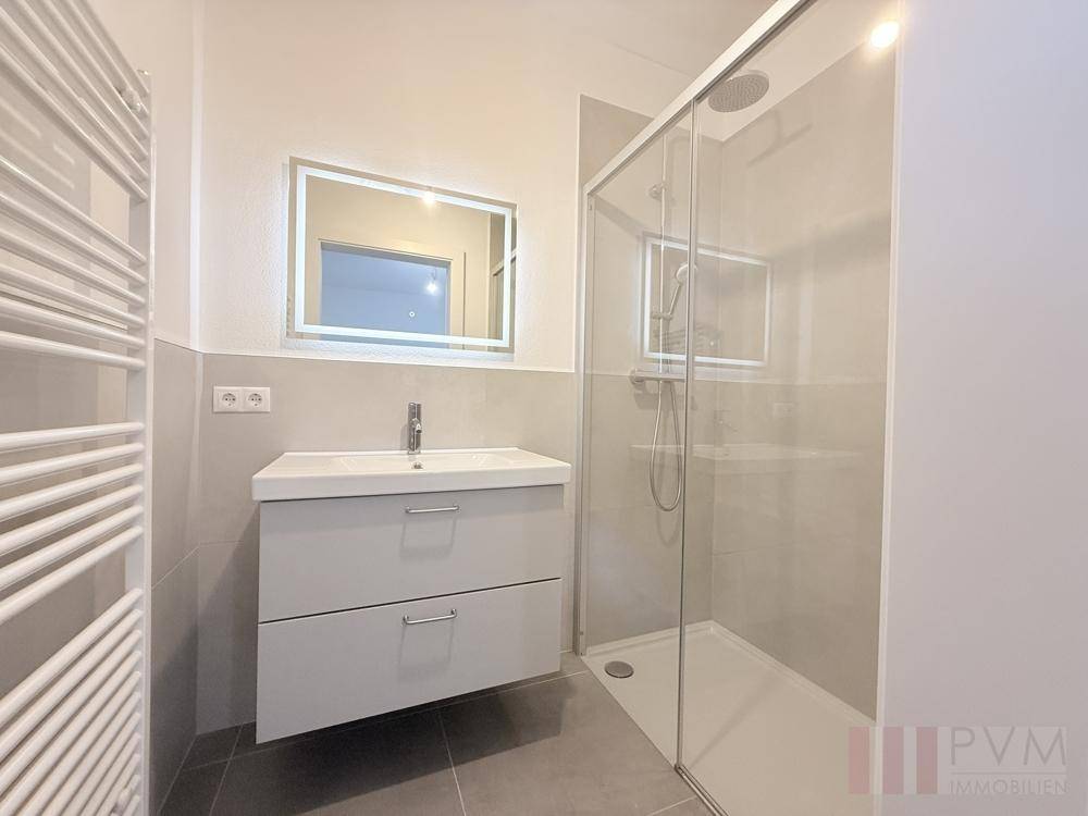 Modernes Badezimmer mit begehbarer Dusche, Einzelwaschbecken und beheiztem Handtuchhalter.