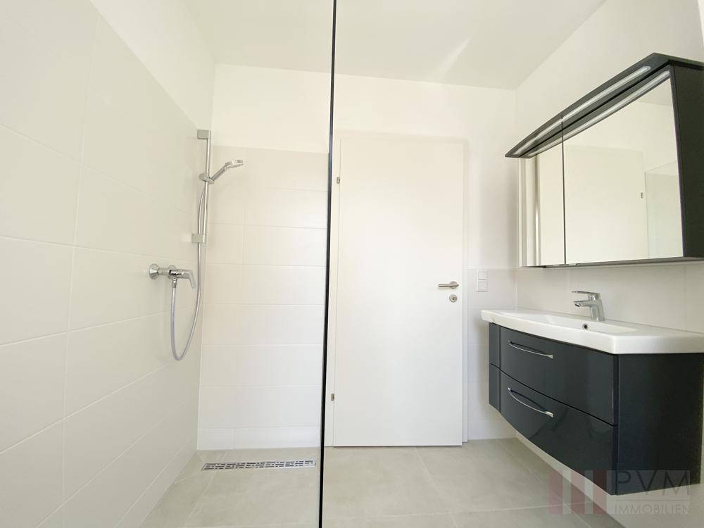 Zeitgemäßes Badezimmer mit ebenerdiger Dusche, Waschtisch und Spiegelschrank.