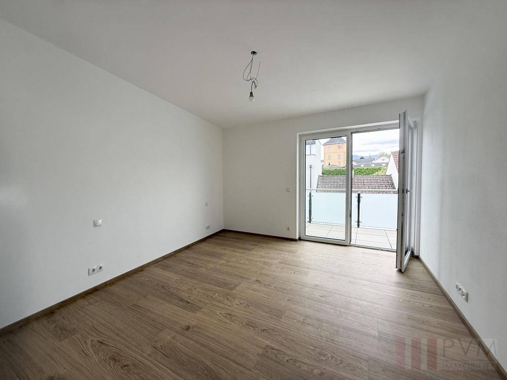Geräumiges Schlafzimmer mit Holzboden und direktem Zugang zu einem Balkon.