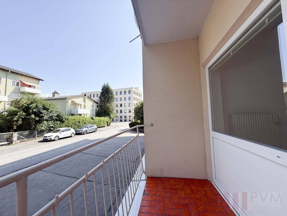 Balkon mit roten Fliesen und Metallgeländer, bietet einen Blick auf die Wohnstraße.