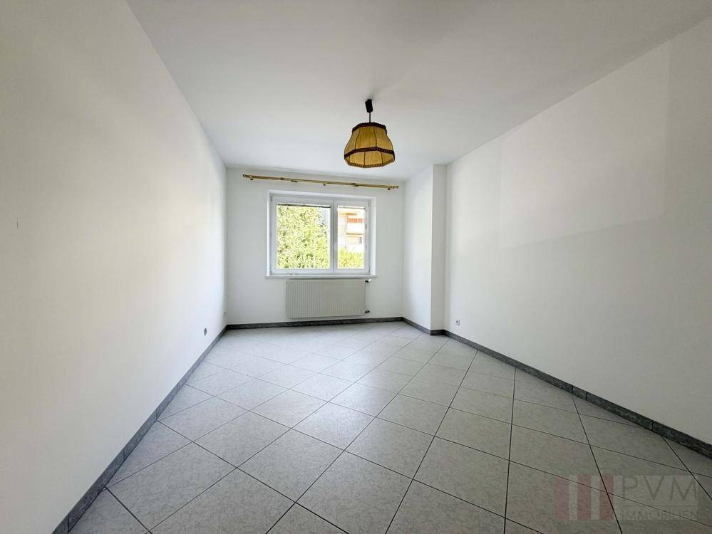 Helles Zimmer mit Fliesenboden und Fenster mit Blick ins Grüne, ideal als Schlafzimmer.