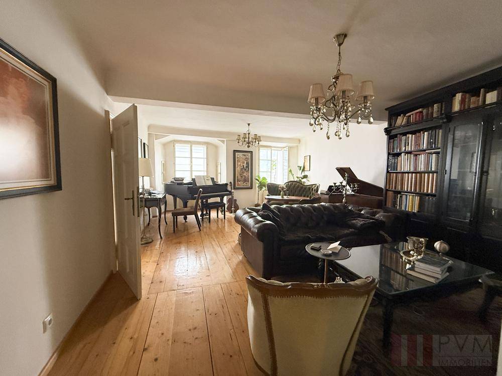 Helles Wohnzimmer mit Holzdielenboden, Ledersofa und Blick auf den Flügel.