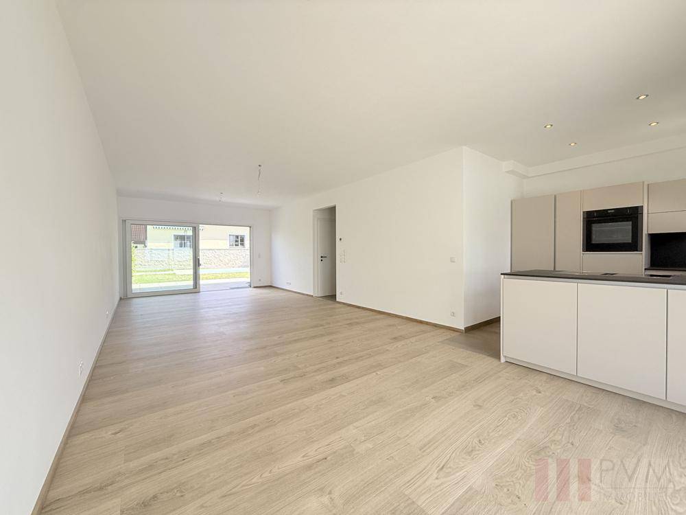 Geräumiger, leerer Wohn-Essbereich mit hellem Holzboden und Zugang zur Terrasse.