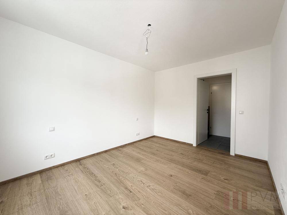Geräumiges, unmöbliertes Schlafzimmer mit Holzboden und Zugang zum Flur.