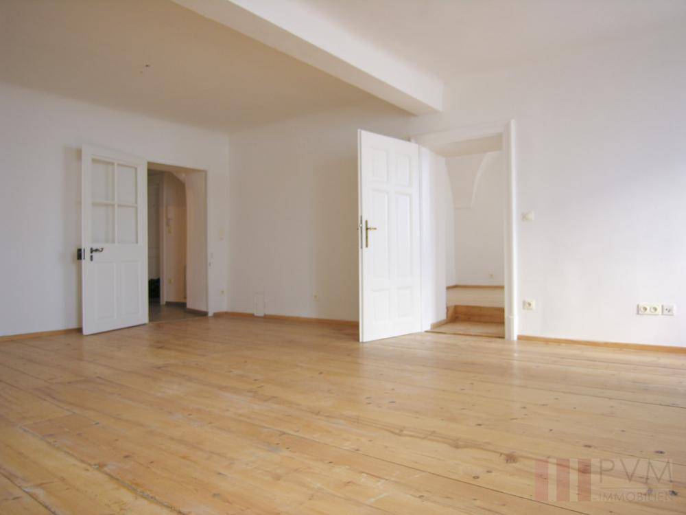 Leerer Raum mit Holzdielenboden und weißen Türen, bereit zur individuellen Gestaltung.