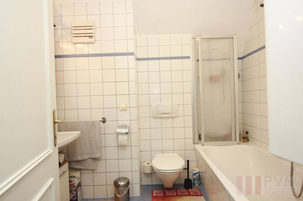 Badezimmer mit Badewanne, Dusche, WC und weißen Fliesen an den Wänden.
