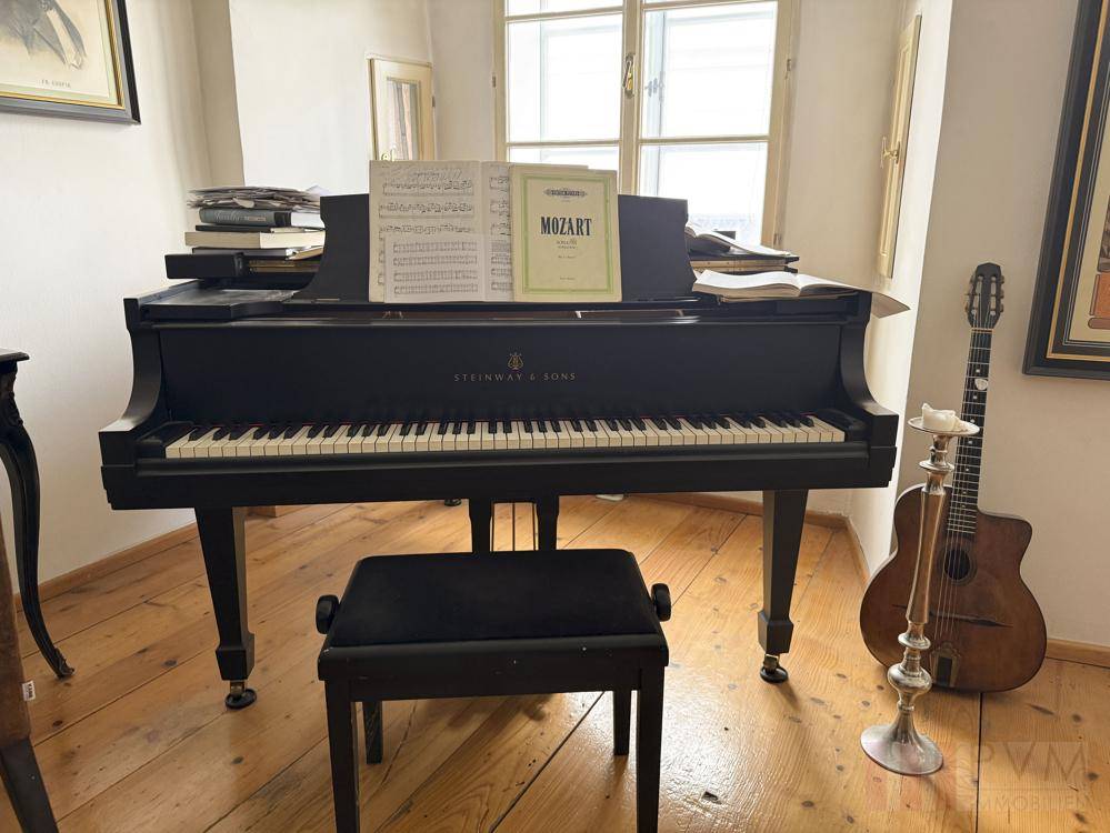 Schwarzer Flügel von Steinway & Sons am Fenster mit Noten und Gitarre.