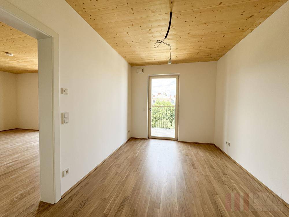 Helles Schlafzimmer mit Holzboden, Holzdecke und Zugang zu einem französischen Balkon.