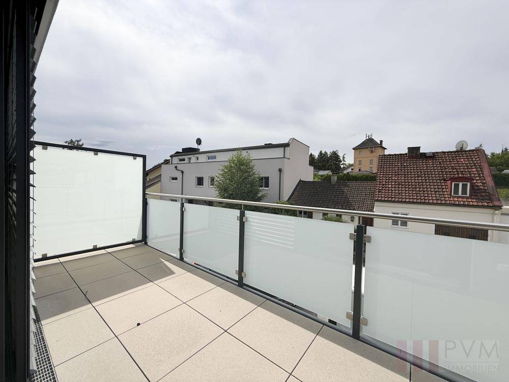 Geräumiger Balkon mit modernen Glasgeländern und Blick auf die umliegenden Gebäude.