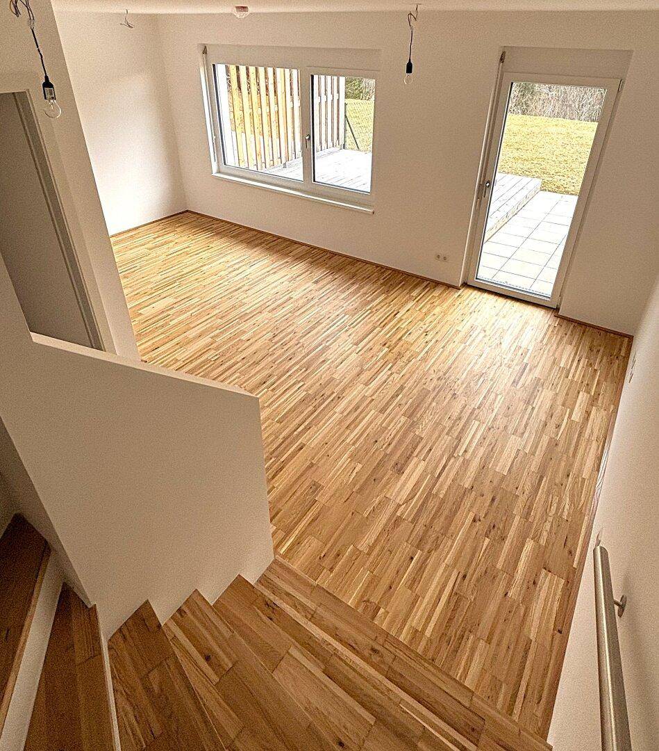 Heller Raum mit Holzboden und Treppe, die zu einem weiteren Bereich führt.