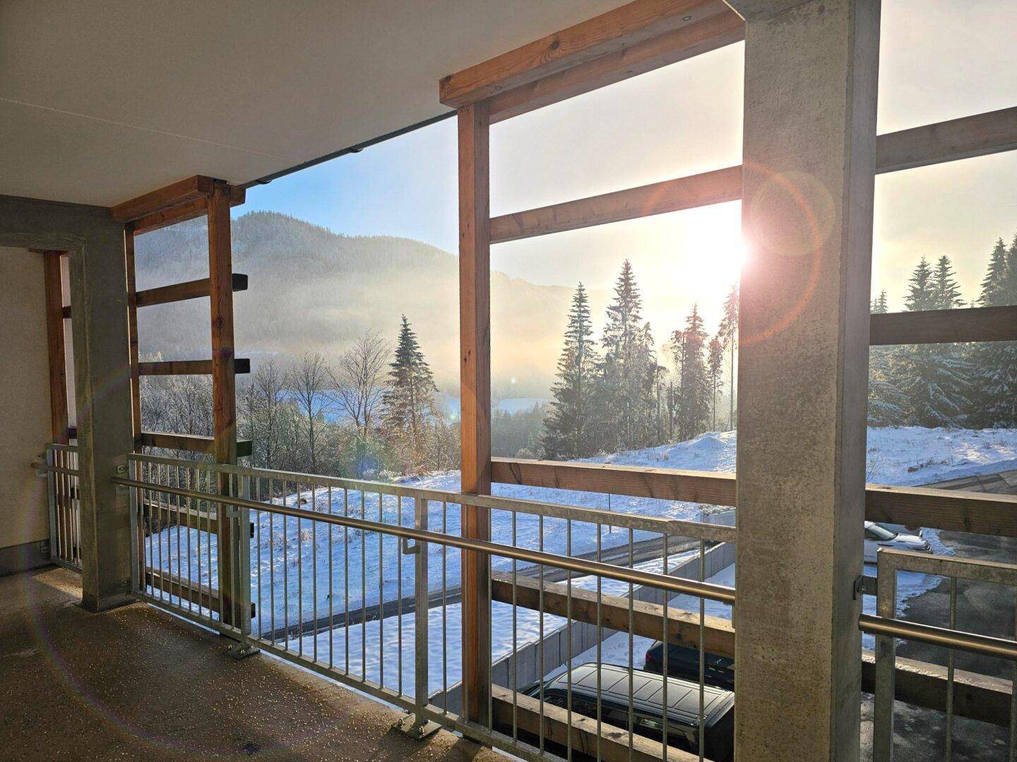 Überdachte Loggia mit Bergblick und See im Hintergrund in winterlicher Morgenstimmung.