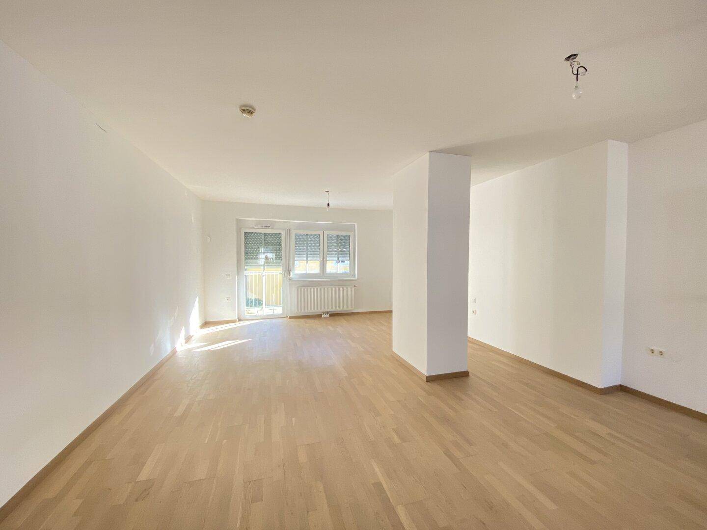 Geräumiger, heller Wohnbereich mit Parkettboden und großen Fenstern mit Rollläden.