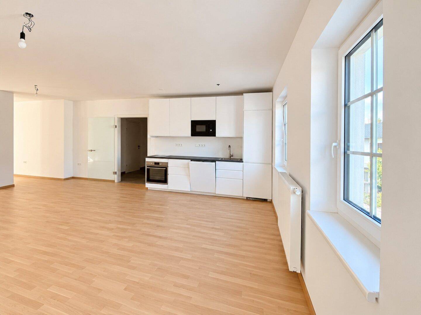 Moderne Einbauküche in einem hellen, offenen Wohnbereich mit Fenster.