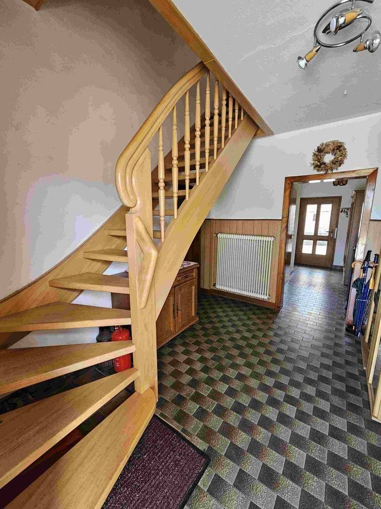 Flur mit einer eleganten Holztreppe und einem gemusterten Fliesenboden.
