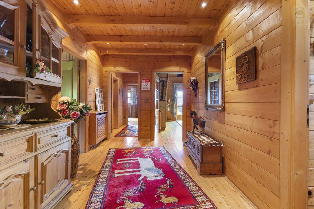 Heller Flur mit Holzvertäfelung, Holzboden und traditionellem Teppich, der zu weiteren Räumen führt.