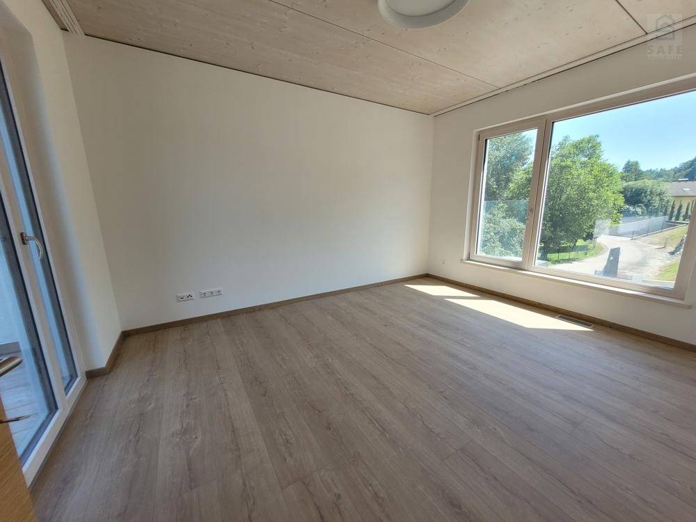 Geräumiges Schlafzimmer mit Holzboden und großer Fensterfront, die Zugang nach draußen bietet.