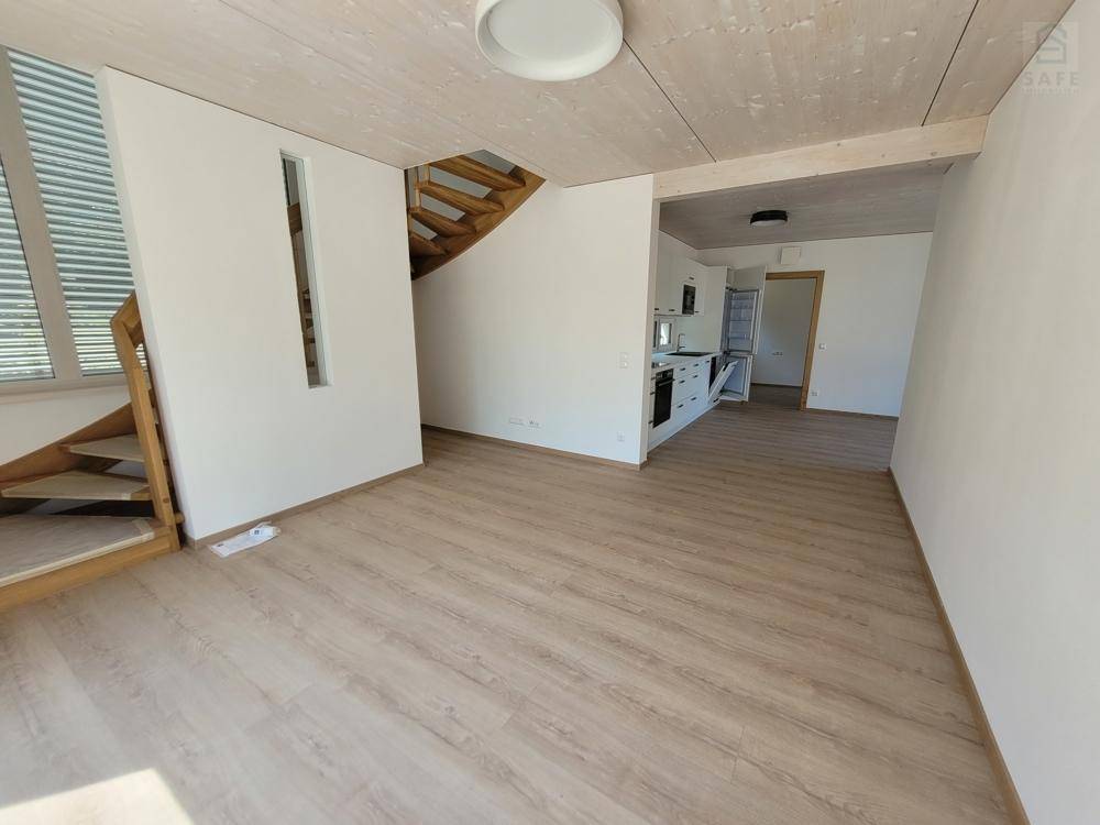 Offener Wohnbereich mit Holzboden, Treppe und Blick auf die angrenzende Küchenzeile.