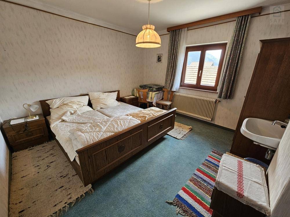 Schlafzimmer mit zwei Einzelbetten, Teppichboden und einem kleinen Waschbecken in der Ecke.