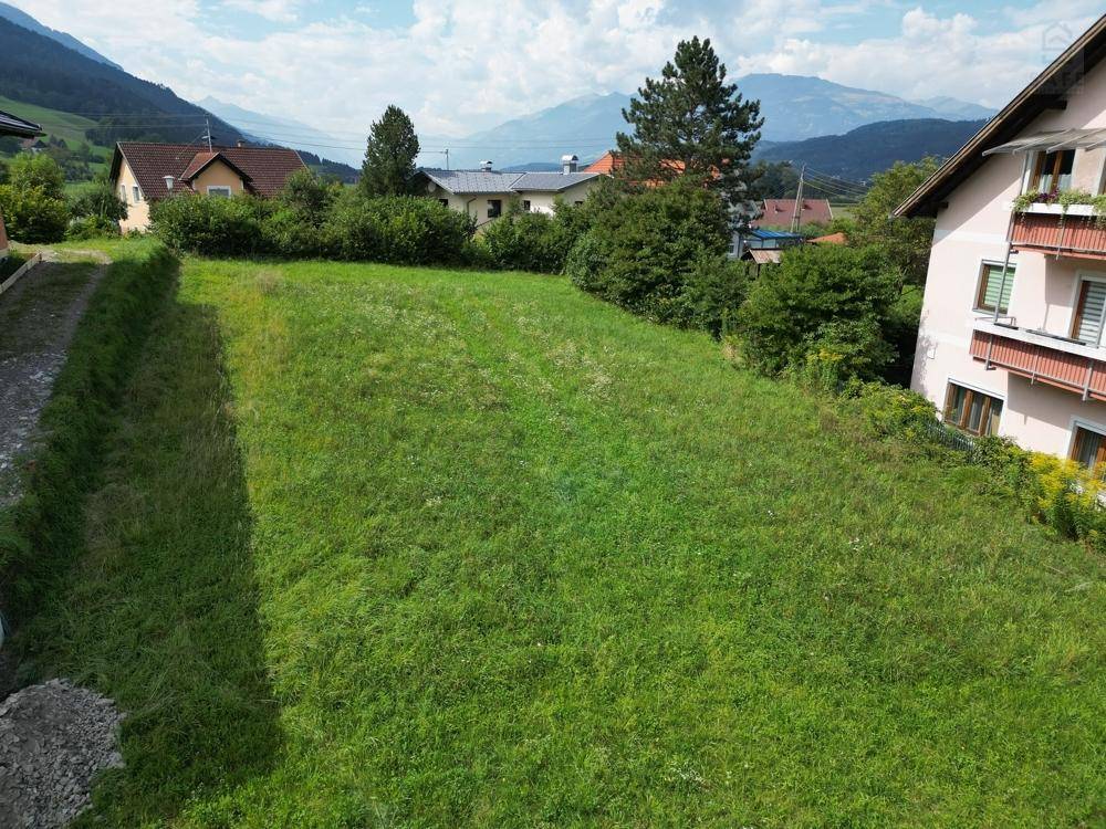 Unbebautes Grundstück mit üppigem Grün und Panoramablick auf die Berge im Hintergrund.
