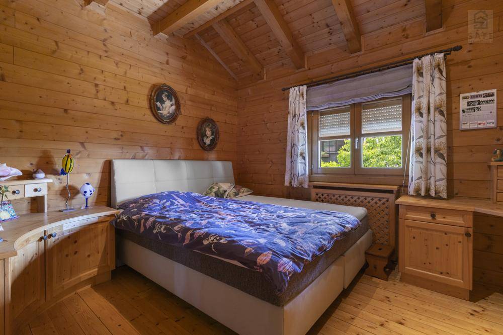 Helles Schlafzimmer mit Holzvertäfelung, Holzboden und einem bequemen Doppelbett.