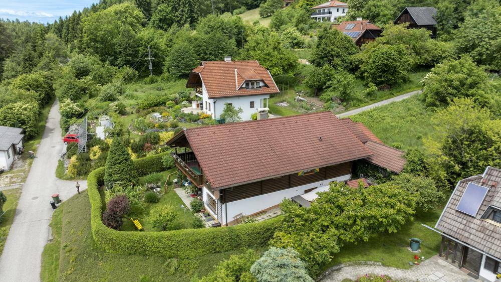 Luftaufnahme der Häuser in einer idyllischen, bewaldeten Umgebung mit roten Dächern und Gärten.